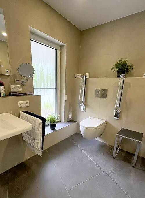 Barrierefreies Badezimmer mit unterfahrbarem Waschbecken und Haltegriffen